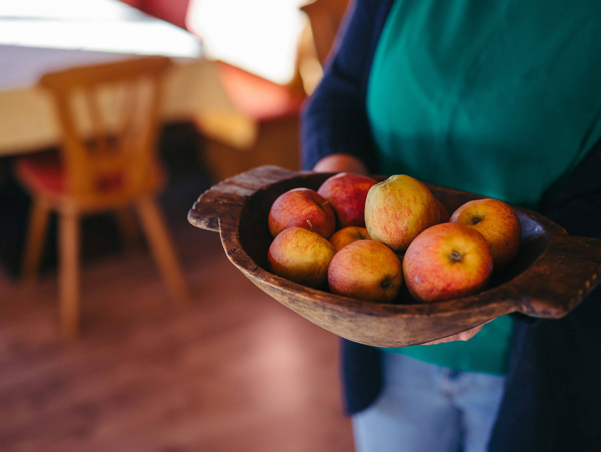 Una donna tiene in mano una ciotola piena di mele - Hofer