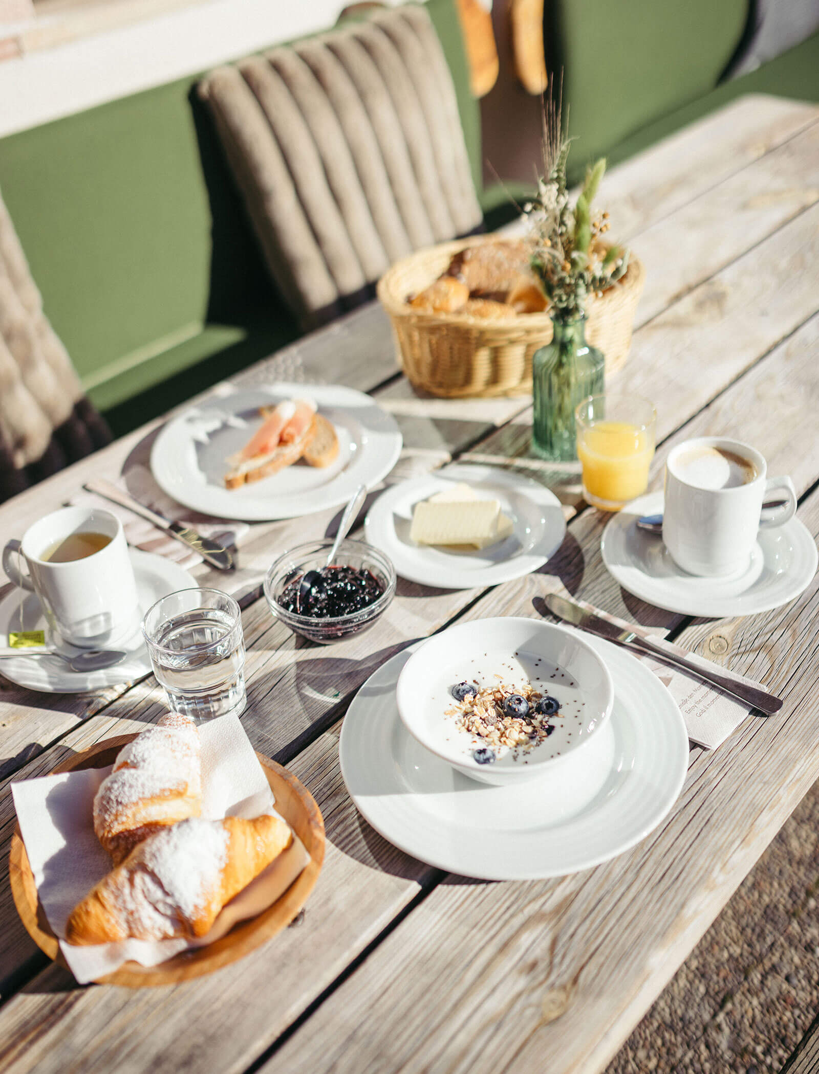 Frühstückstisch im Freien mit Joghurt, Croissants, Brot und Kaffee - Hofer